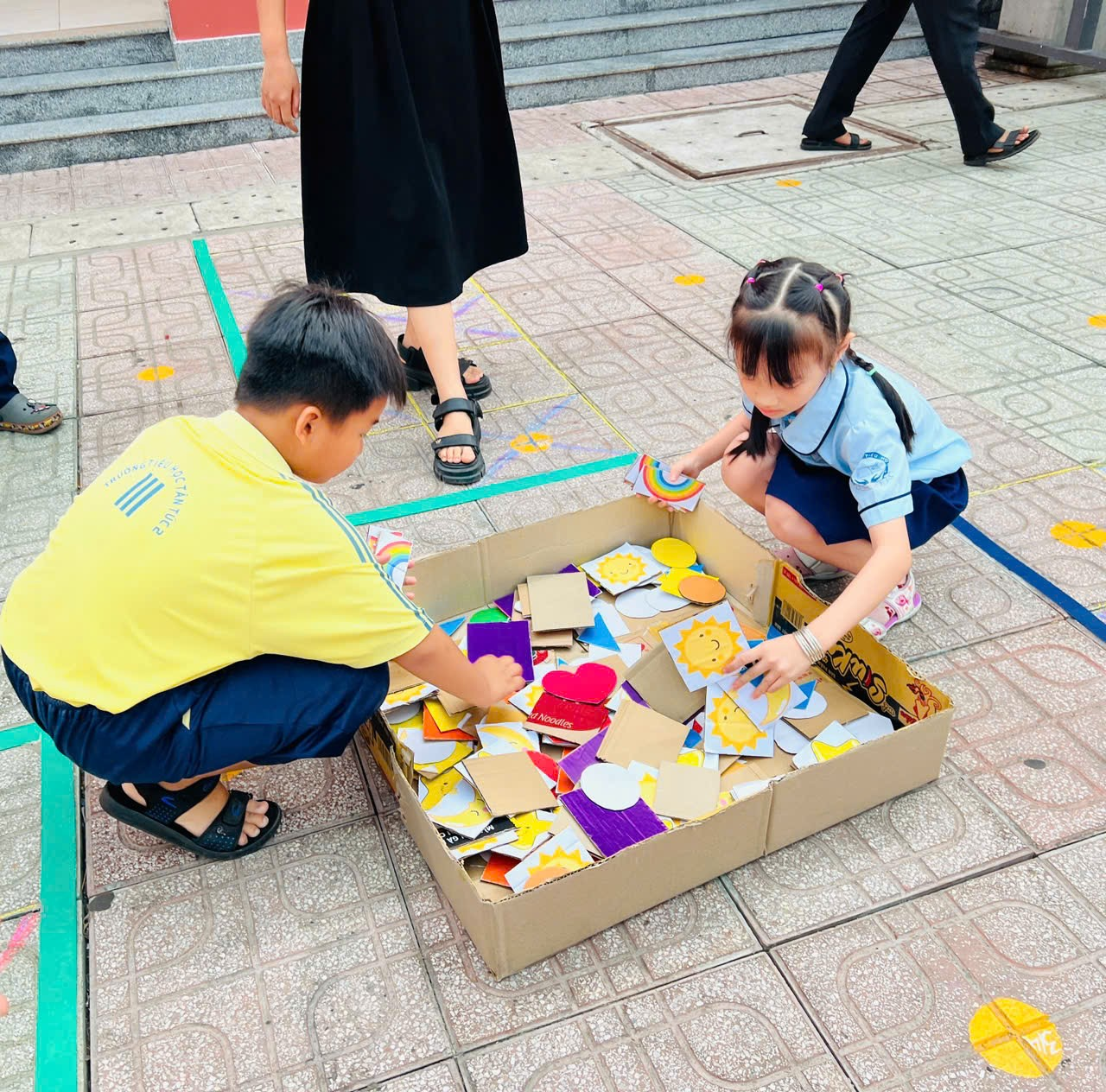A child and child playing with paper pieces in a box Description automatically generated