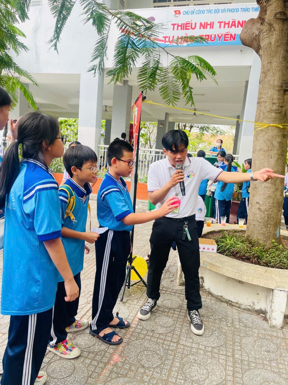 A group of kids standing around a person holding a microphone Description automatically generated