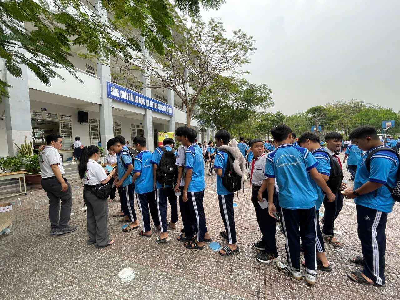 A group of people standing in a line outside a building Description automatically generated